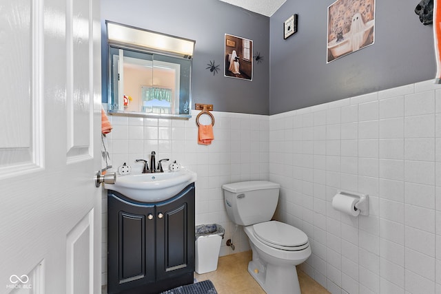 bathroom featuring tile walls, toilet, wainscoting, vanity, and tile patterned flooring