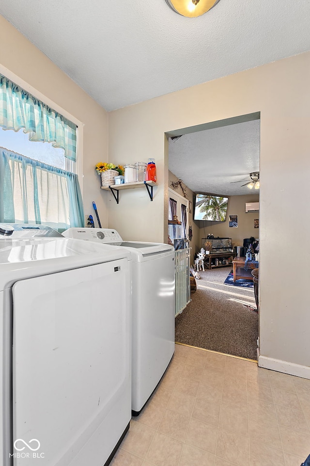 washroom featuring a textured ceiling, laundry area, baseboards, an AC wall unit, and washer and clothes dryer