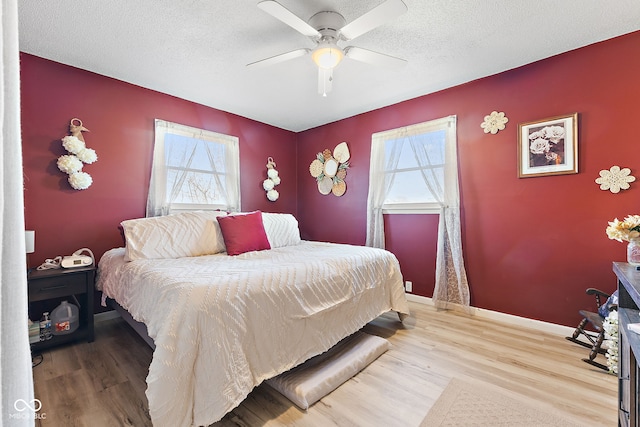 bedroom featuring ceiling fan, a textured ceiling, baseboards, and wood finished floors