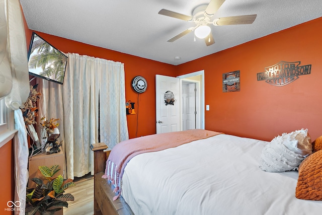 bedroom with a textured ceiling, a ceiling fan, and wood finished floors