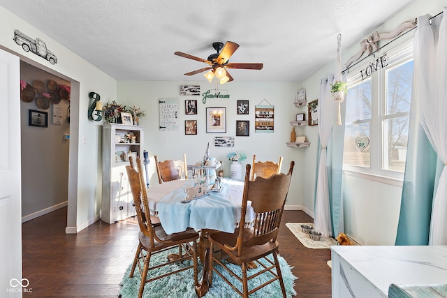 dining space featuring dark wood-type flooring, a textured ceiling, baseboards, and a ceiling fan