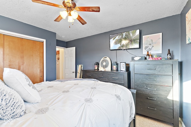 bedroom with a ceiling fan, a closet, light colored carpet, and a textured ceiling