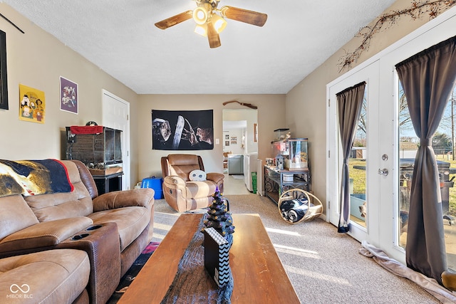 living room featuring a textured ceiling, a ceiling fan, french doors, and light colored carpet