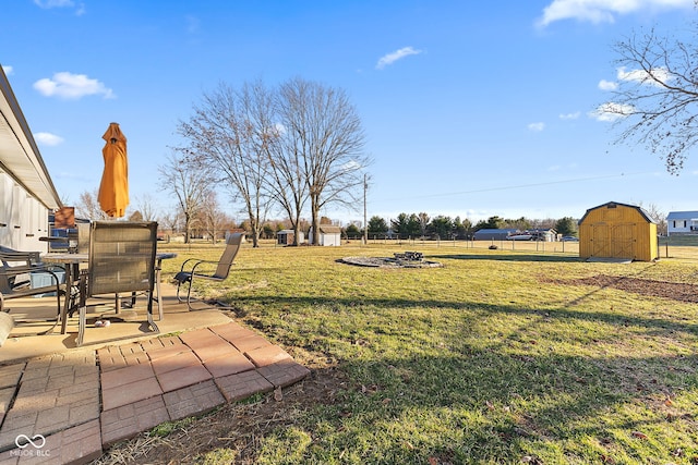 view of yard with a shed, fence, an outdoor structure, and a patio