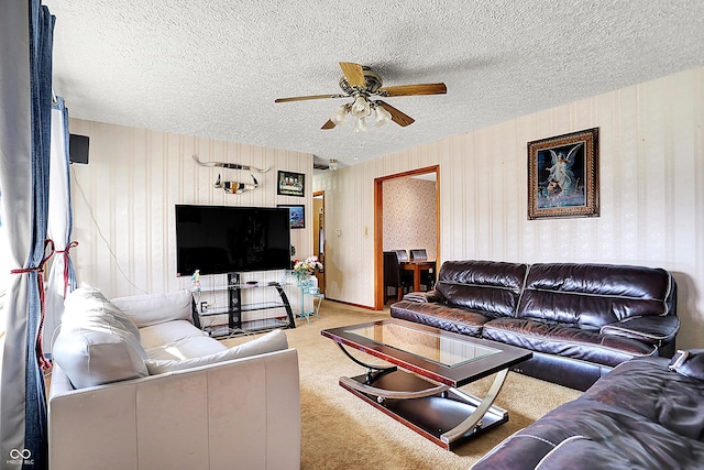 living room featuring wallpapered walls, a textured ceiling, a ceiling fan, and carpet flooring