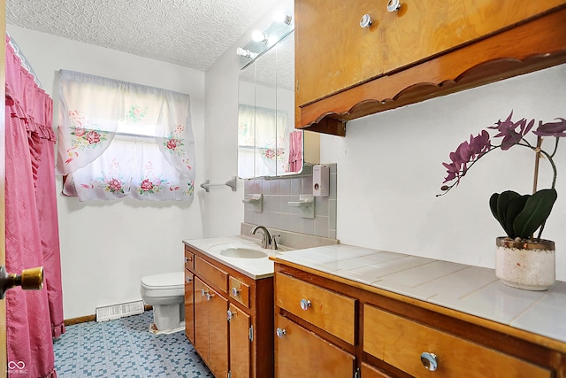 bathroom with a textured ceiling, toilet, visible vents, vanity, and baseboards