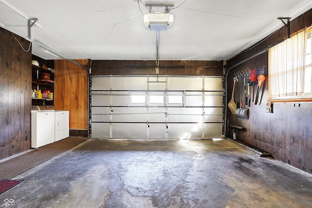 garage featuring a garage door opener, wooden walls, and separate washer and dryer