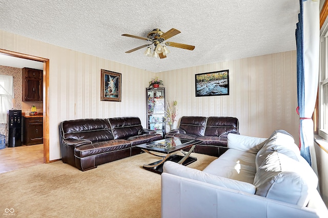 living area with a ceiling fan, a textured ceiling, and light colored carpet