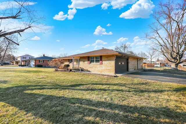 view of front of home with aphalt driveway, a front lawn, an attached garage, and brick siding