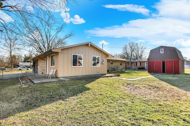 rear view of property with a barn, a patio, an outbuilding, fence, and a yard