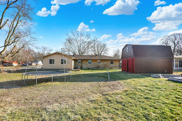 rear view of house featuring a trampoline, an outbuilding, a lawn, and a barn