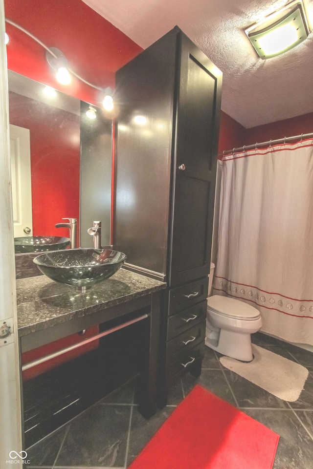 full bath with toilet, a textured ceiling, vanity, and tile patterned floors