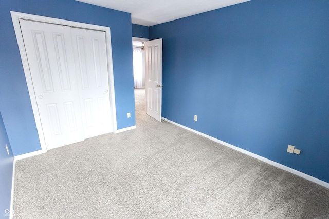 unfurnished bedroom with carpet floors, a closet, and baseboards