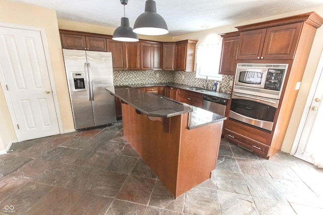 kitchen with stainless steel appliances, a sink, backsplash, dark stone counters, and stone finish floor