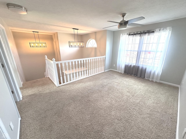 carpeted empty room with ceiling fan with notable chandelier, a textured ceiling, and baseboards