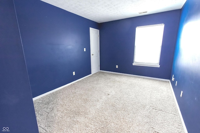 carpeted spare room with a textured ceiling, visible vents, and baseboards