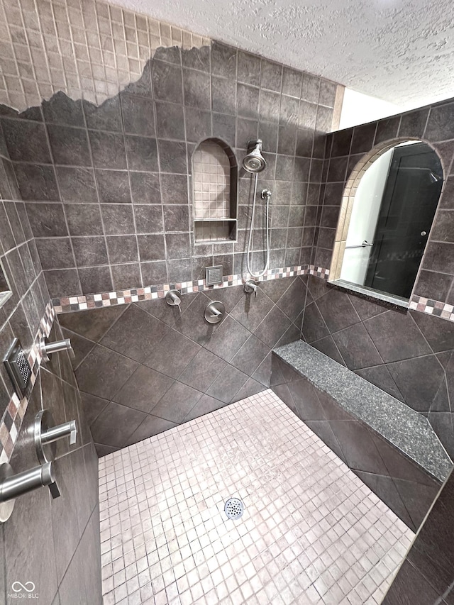 full bath with a tile shower and a textured ceiling