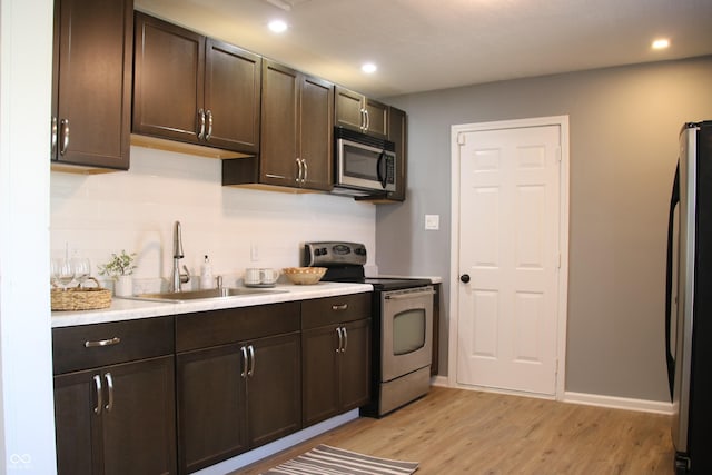 kitchen with a sink, stainless steel appliances, dark brown cabinets, and light countertops