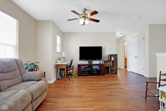 living room with baseboards, plenty of natural light, ceiling fan, and light wood finished floors