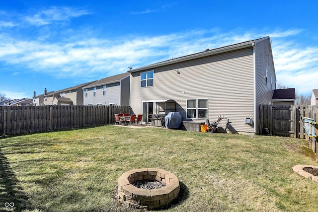 rear view of property featuring a patio, a lawn, a fenced backyard, and an outdoor fire pit