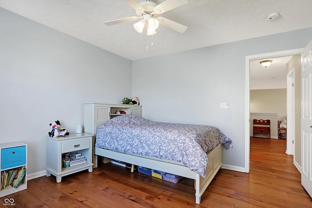 bedroom featuring a textured ceiling, wood finished floors, baseboards, and ceiling fan