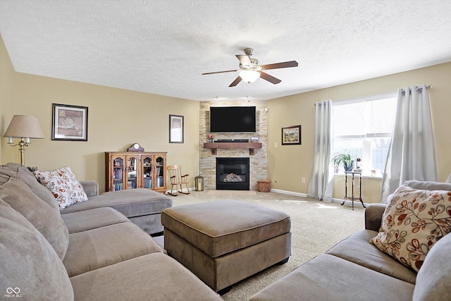 living area featuring light carpet, a ceiling fan, a textured ceiling, a fireplace, and baseboards