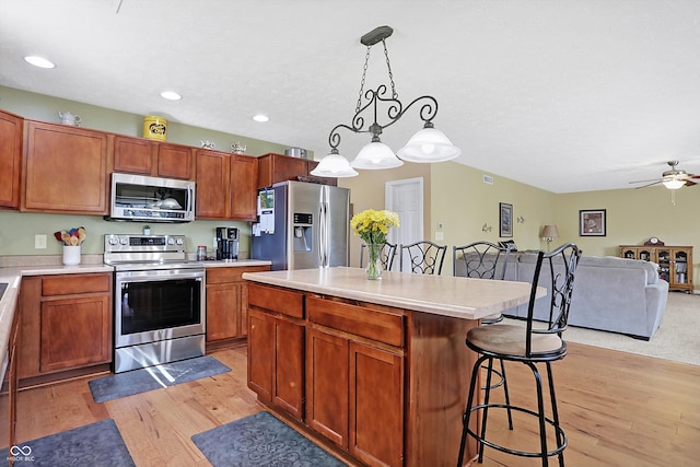 kitchen featuring light wood-style flooring, appliances with stainless steel finishes, a breakfast bar, and light countertops