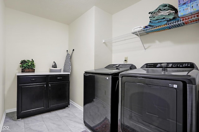 washroom featuring baseboards, cabinet space, and independent washer and dryer