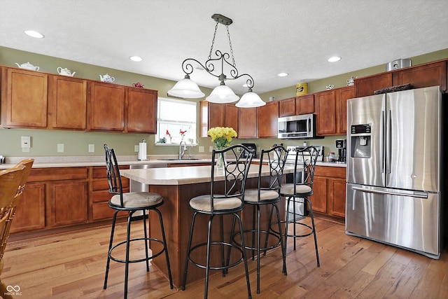 kitchen with a breakfast bar, light countertops, light wood-type flooring, and stainless steel appliances