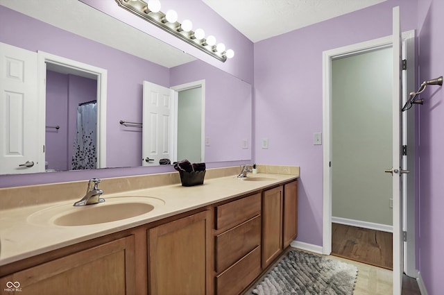 full bath featuring double vanity, baseboards, and a sink