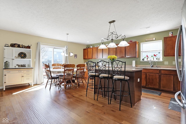 kitchen with a wealth of natural light, a kitchen bar, a sink, dark wood-style floors, and a center island