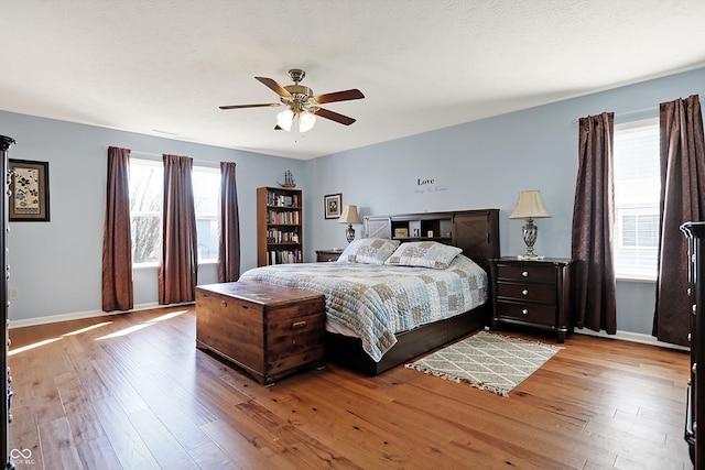 bedroom with baseboards, wood-type flooring, a textured ceiling, and ceiling fan