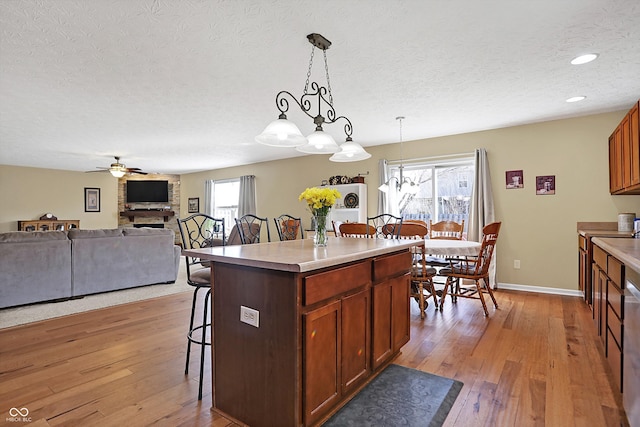 kitchen with a kitchen breakfast bar, plenty of natural light, a ceiling fan, and light wood-style floors