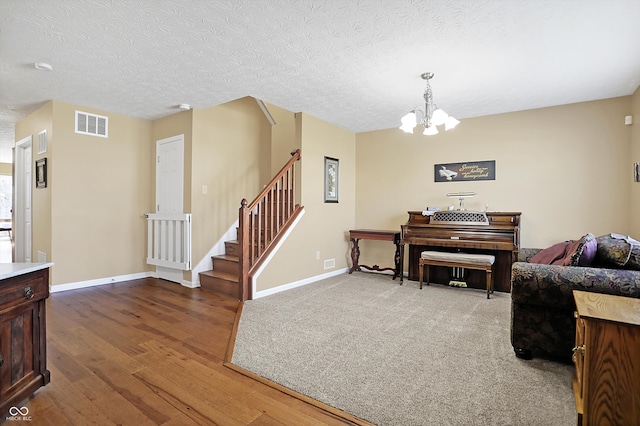 interior space featuring stairway, baseboards, visible vents, a textured ceiling, and a chandelier