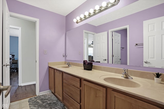 bathroom featuring double vanity, baseboards, and a sink