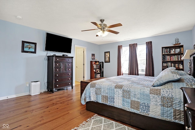 bedroom with baseboards, wood finished floors, and a ceiling fan