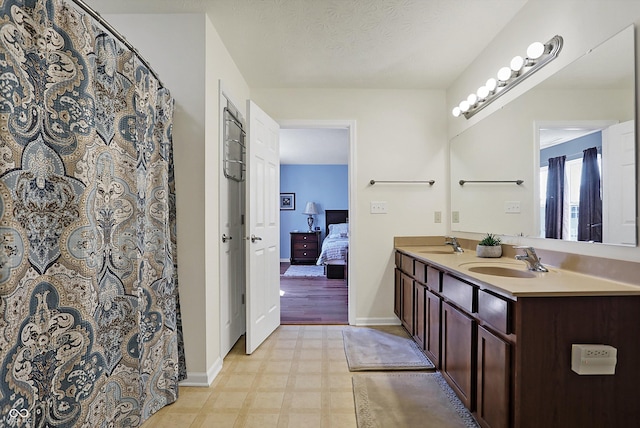 ensuite bathroom featuring tile patterned floors, connected bathroom, double vanity, and a sink