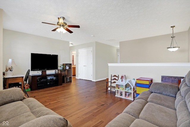 living room featuring baseboards, a textured ceiling, wood finished floors, and a ceiling fan