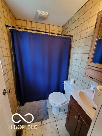 bathroom featuring curtained shower, tile patterned flooring, toilet, vanity, and tile walls