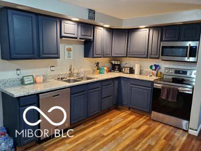 kitchen featuring appliances with stainless steel finishes, light wood-type flooring, blue cabinets, and a sink