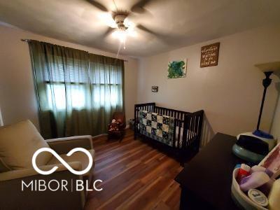 bedroom featuring a nursery area, ceiling fan, and wood finished floors