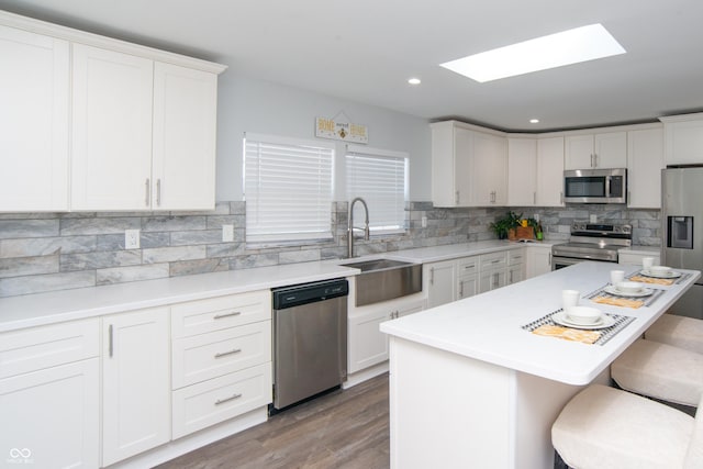 kitchen featuring white cabinetry, a kitchen bar, appliances with stainless steel finishes, and a sink