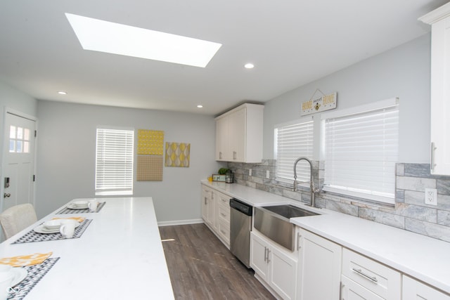 kitchen featuring white cabinets, light countertops, dishwasher, and a sink