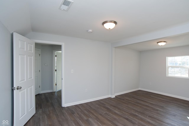 empty room featuring dark wood-style floors, visible vents, and baseboards