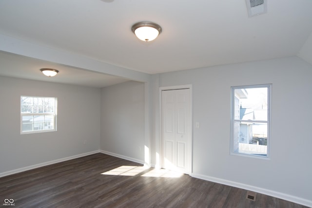 unfurnished room with dark wood-style floors, baseboards, and visible vents