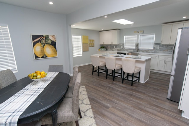 kitchen featuring a breakfast bar, a center island, freestanding refrigerator, and white cabinetry