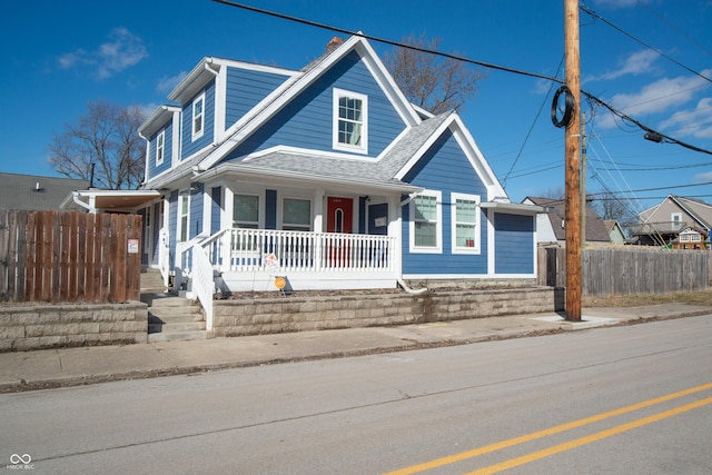 view of front of house featuring a porch, fence, and a shingled roof