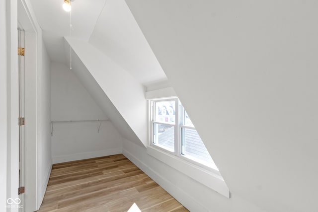 bonus room with vaulted ceiling, light wood-style flooring, and baseboards