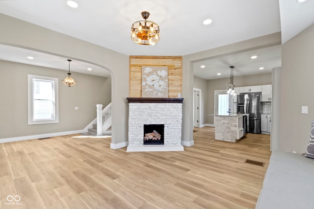 unfurnished living room featuring visible vents, light wood finished floors, recessed lighting, stairs, and a notable chandelier