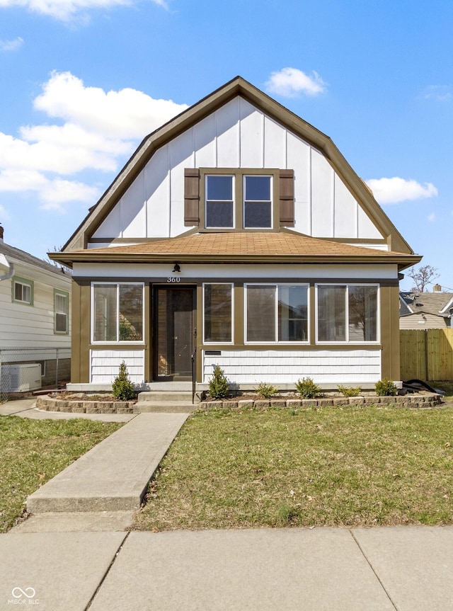 view of front of house with board and batten siding, a front lawn, and fence